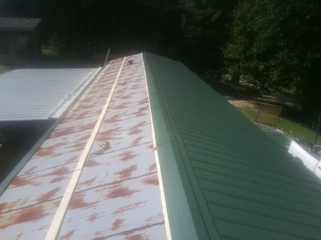 Old rusted panels beside newly installed green metal roofing — Wind Damage Roof Repair by Roofing Brothers in Angelus Oaks