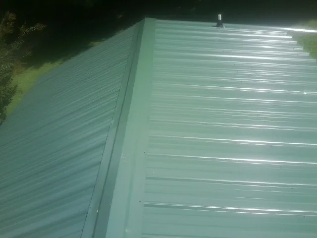 New green metal panels meeting at the ridge of a roof — Flat Roof Repair work by our crew in Angelus Oaks