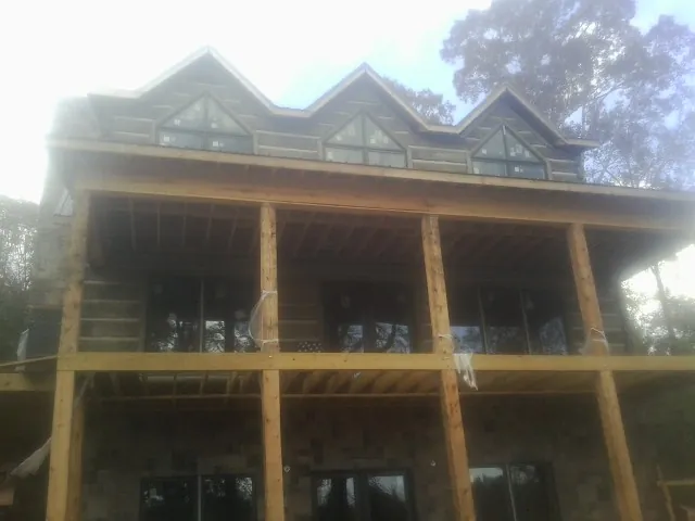 Dormers and porch framing on a large log home under construction — Roof Coating work by our crew in Angelus Oaks