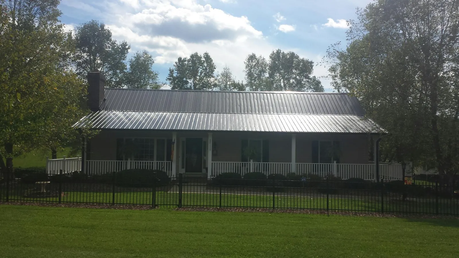 Gray metal roof on a brick ranch with a full width front porch — Gutter Guard Installation work by our crew in Angelus Oaks