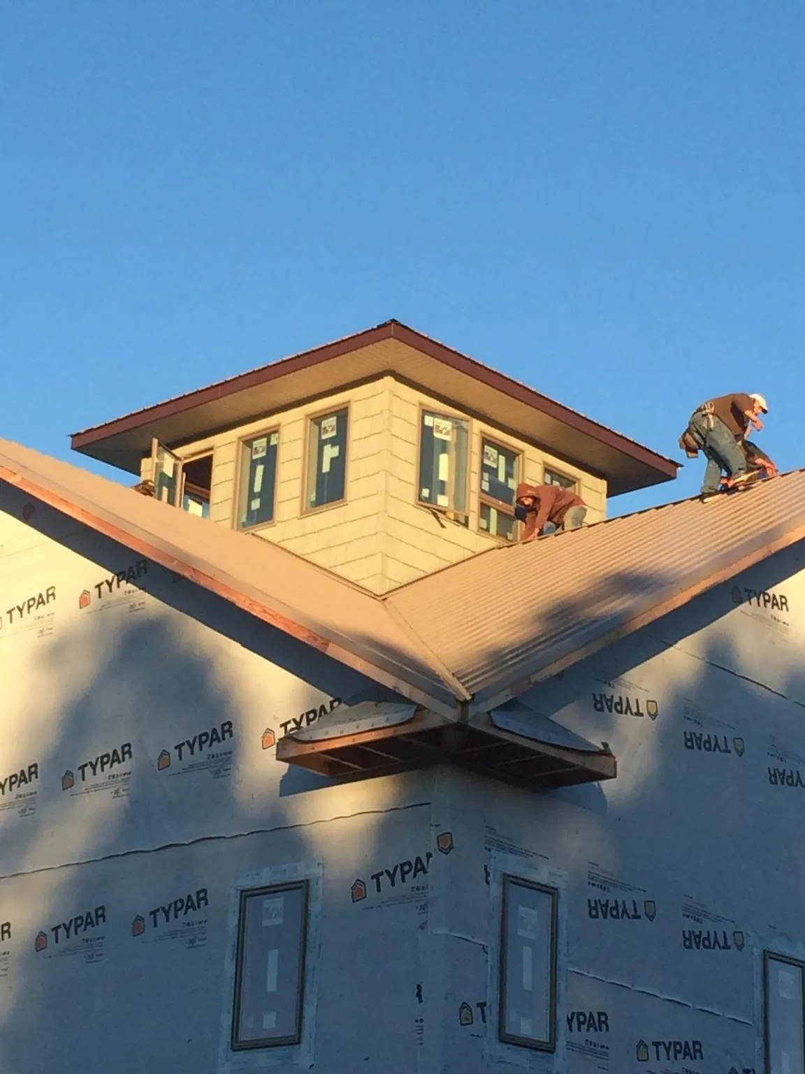 Roofers working around a rooftop cupola on a new metal roof at sunset — Roof Waterproofing in Angelus Oaks by Roofing Brothers